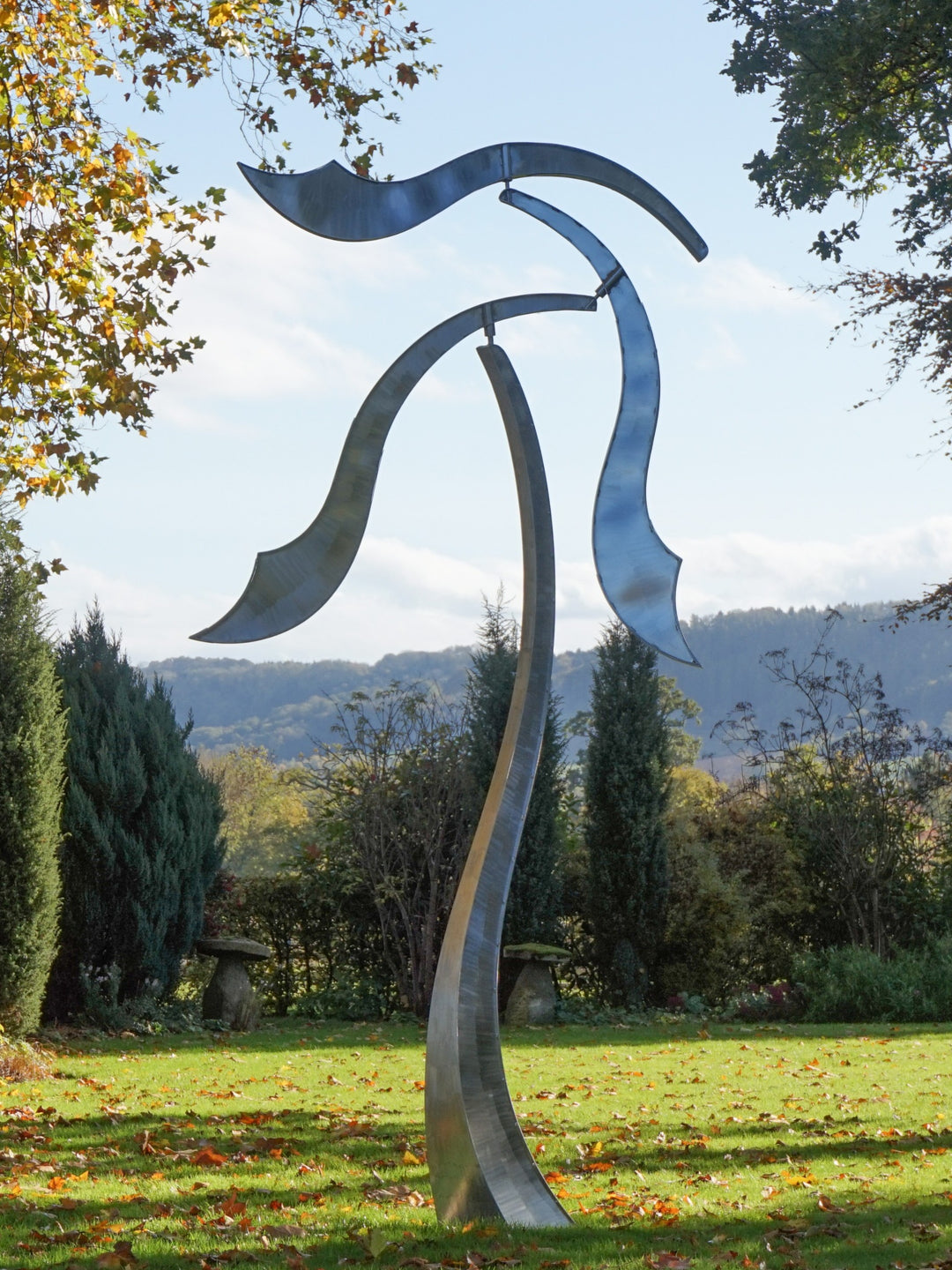 Abstract stainless steel kinetic sculpture with wind-responsive curved elements designed to shift and flow with natural movement