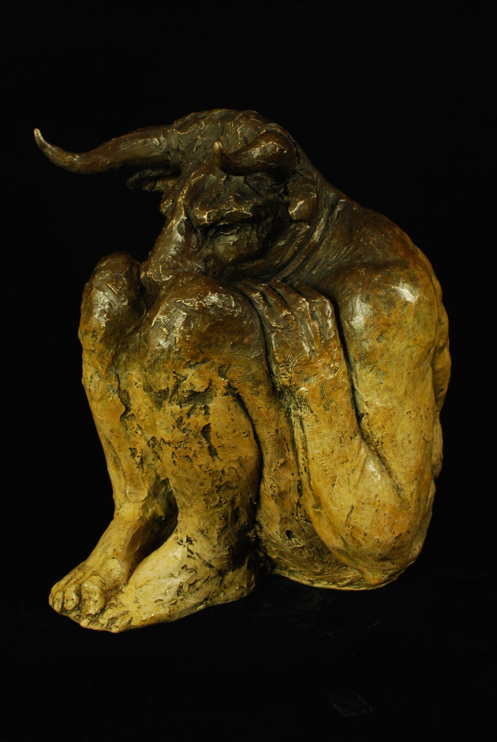 Bronze figurative sculpture by Eve Shepherd depicting a crouching Minotaur curled inward, horned head bowed and body folded low, conveying vulnerability and introspection through a textured, dark patinated surface against a black background.