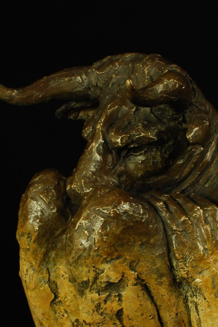 Bronze figurative sculpture by Eve Shepherd depicting a crouching Minotaur curled inward, horned head bowed and body folded low, conveying vulnerability and introspection through a textured, dark patinated surface against a black background.