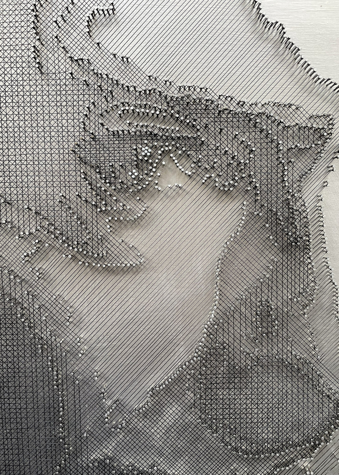 Portrait of David Bowie constructed from fine black enamelled copper wire tensioned around thousands of small metal nails on a silver acrylic painted board, forming dense linear layers that define facial features, hair and expression through tonal variation, depth and shadow across a rigid rectangular surface.