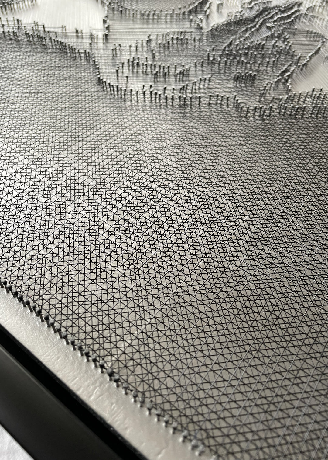 Portrait of David Bowie constructed from fine black enamelled copper wire tensioned around thousands of small metal nails on a silver acrylic painted board, forming dense linear layers that define facial features, hair and expression through tonal variation, depth and shadow across a rigid rectangular surface.