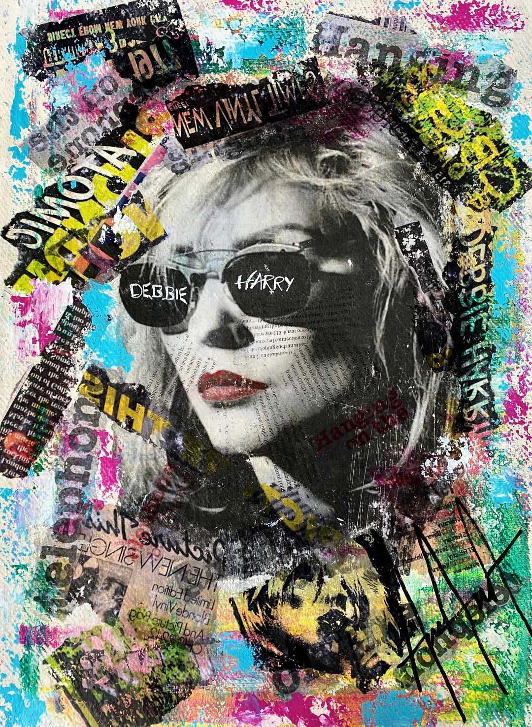 “Debbie Harry by Andolini Art – mixed media on paper portrait of Blondie singer Debbie Harry with sunglasses inscribed with her name, surrounded by layered text, collage and graffiti-style splashes of pink, yellow, blue and black.”