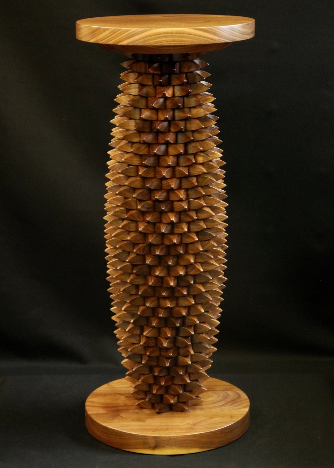 One-off sculptural table in black walnut with a cylindrical base of interlocking, spike-like wooden tessellations, topped and grounded by smooth circular planes, blending function and organic form.