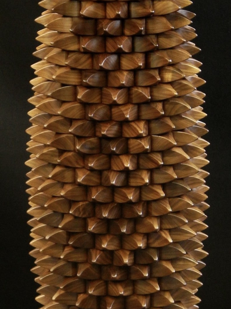 One-off sculptural table in black walnut with a cylindrical base of interlocking, spike-like wooden tessellations, topped and grounded by smooth circular planes, blending function and organic form.