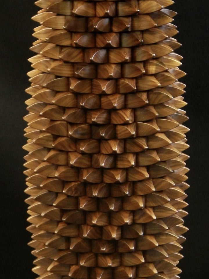 One-off sculptural table in black walnut with a cylindrical base of interlocking, spike-like wooden tessellations, topped and grounded by smooth circular planes, blending function and organic form.