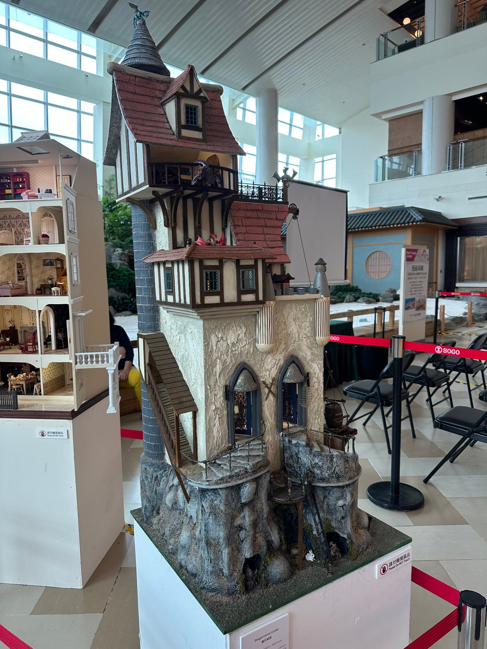 Handcrafted fantasy-style dolls house with a steep gabled roof, stone base, and intricate Tudor details on multiple levels.