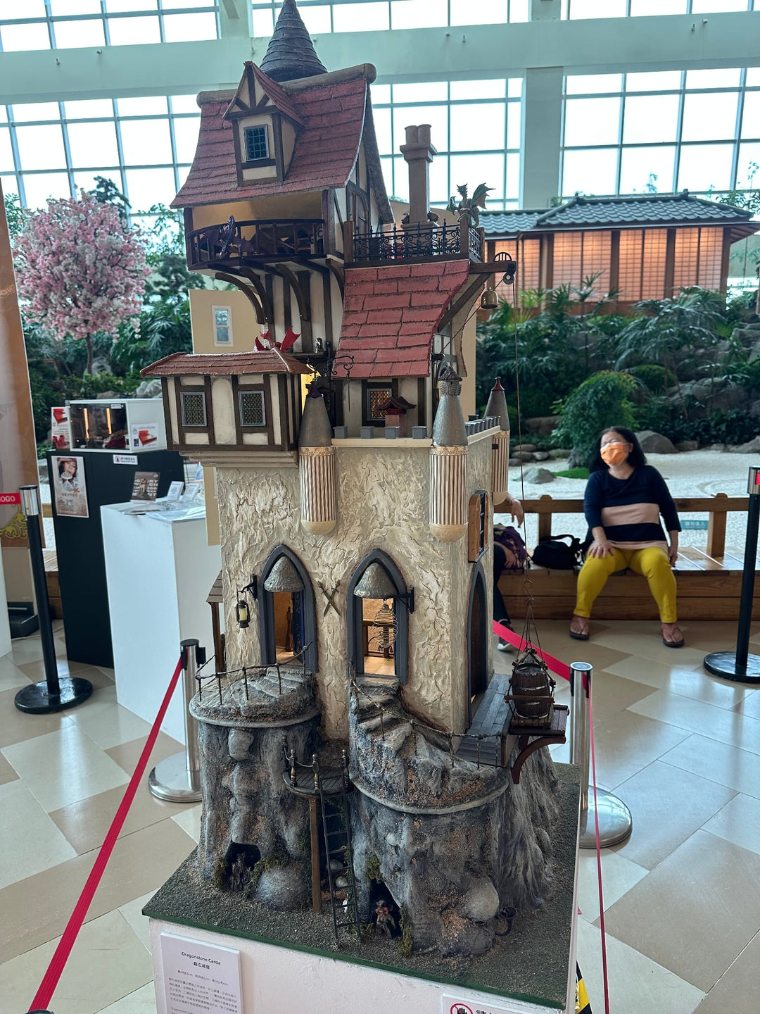 Handcrafted fantasy-style dolls house with a steep gabled roof, stone base, and intricate Tudor details on multiple levels.