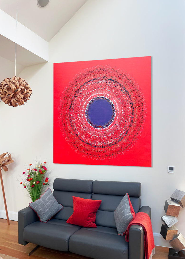 Large abstract painting “Ellipsis” by Swarez — bold square composition with a deep violet central circle surrounded by concentric rings of paint droplets and splashes on a vivid matte red background. Energetic, dynamic halo effect created by spin technique.