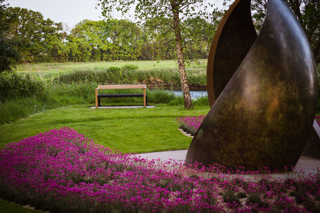 Simon Gudgeon bronze sculpture Embrace featuring monumental abstract curved bronze forms rising upwards and meeting at a central point within a landscaped garden setting.