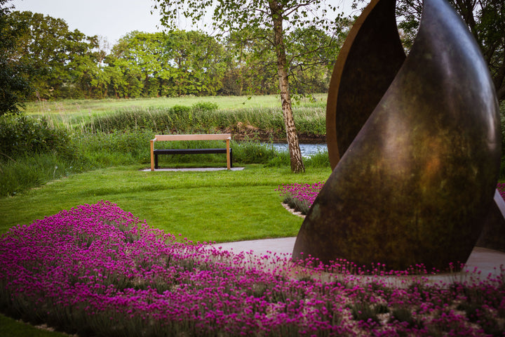 Simon Gudgeon bronze sculpture Embrace featuring monumental abstract curved bronze forms rising upwards and meeting at a central point within a landscaped garden setting.