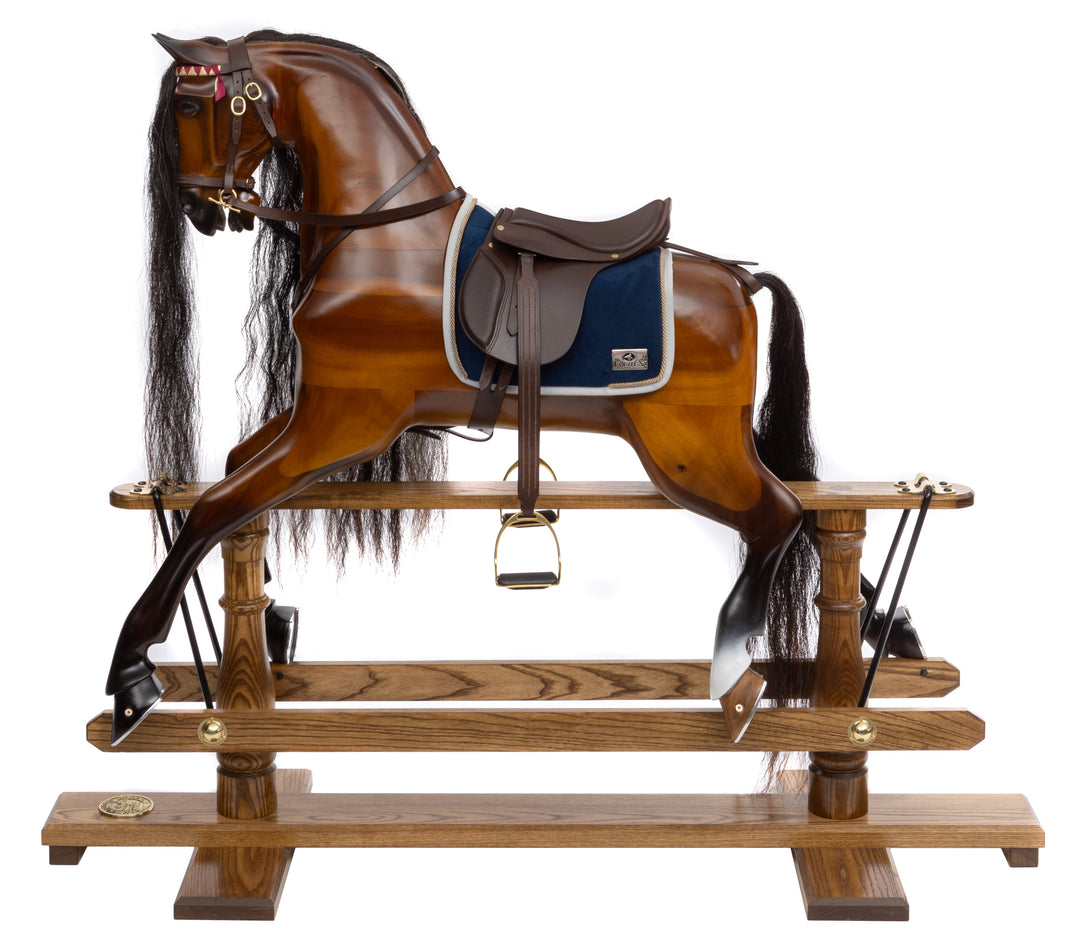 Polished wooden rocking horse with dark mane, blue saddle cloth, and leather tack, displayed on an oak safety stand.
