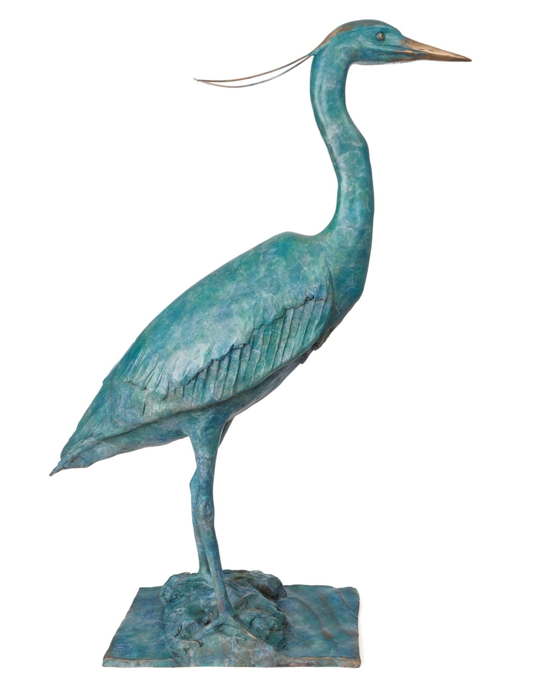‘Erodios’ by Pat Bull, a limited-edition life-size bronze wildlife sculpture depicting a heron standing upright with an elongated curved neck, slender legs, pointed bronze beak and finely textured folded wings. Finished in a rich turquoise, teal and blue-green verdigris patina with subtle earthy bronze highlights, the bird features delicate trailing head feathers and stands on a rectangular naturalistic bronze base with sculpted rocks, capturing the graceful appearance of this distinctive wading bird. 