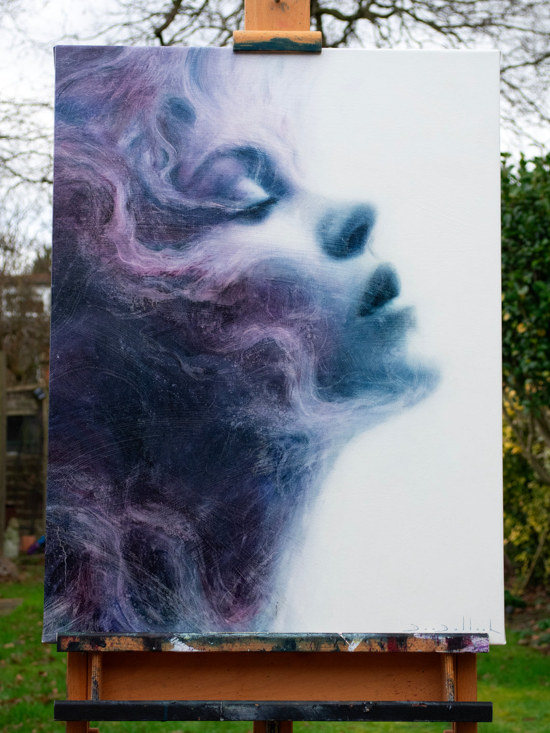 Oil on canvas painting by Dan Bullock, titled Eternal. A dreamlike portrait of a woman’s face in profile, eyes closed, emerging from swirling textures of deep indigo, violet, and soft lavender. The ethereal brushwork gives the impression of smoke or mist, creating a sense of serenity, timelessness, and transcendence.