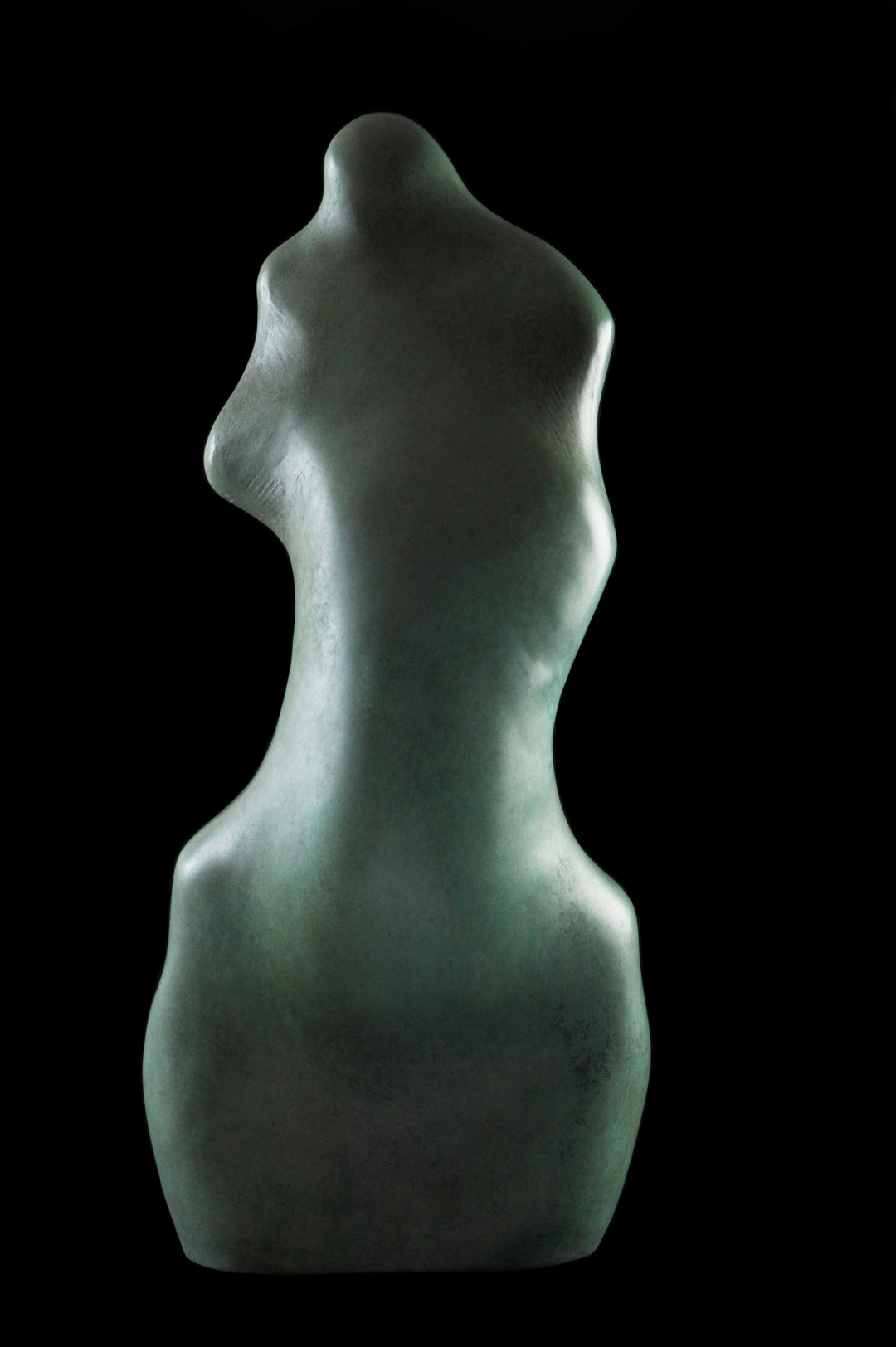Bronze sculpture of an abstract female torso by Nicola Godden, with smooth organic curves and a softly polished surface, standing on a plinth outdoors against a clear blue sky, the form evoking the human body through simplified, flowing contours and natural balance.