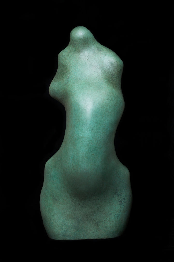 Bronze sculpture of an abstract female torso by Nicola Godden, with smooth organic curves and a softly polished surface, standing on a plinth outdoors against a clear blue sky, the form evoking the human body through simplified, flowing contours and natural balance.