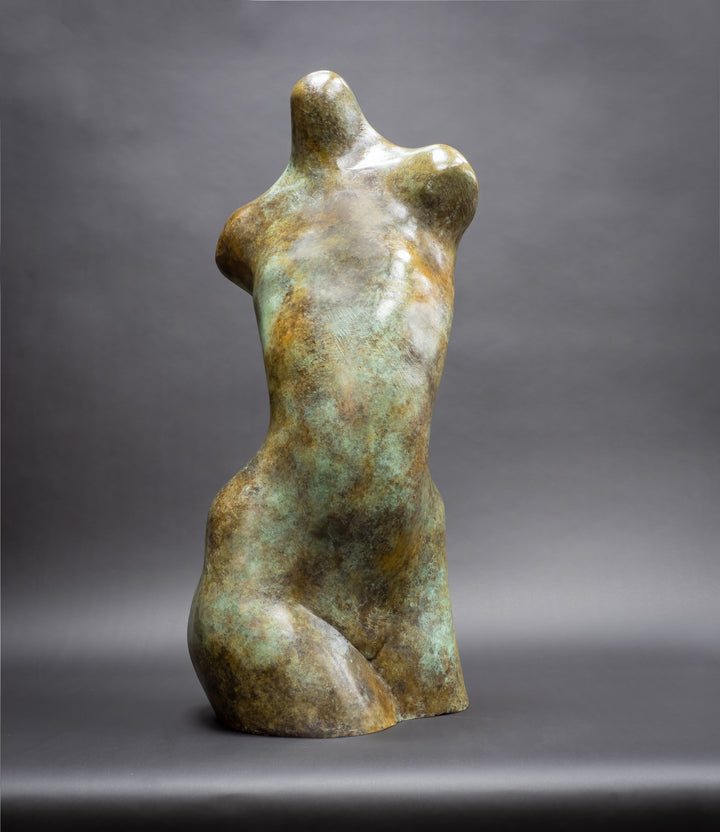Bronze abstract female torso sculpture by Nicola Godden, with softly curved organic form and smooth hand-finished surface, standing on a plinth outdoors, evoking sensuality, balance and metamorphosis through simplified human anatomy and tactile patination.