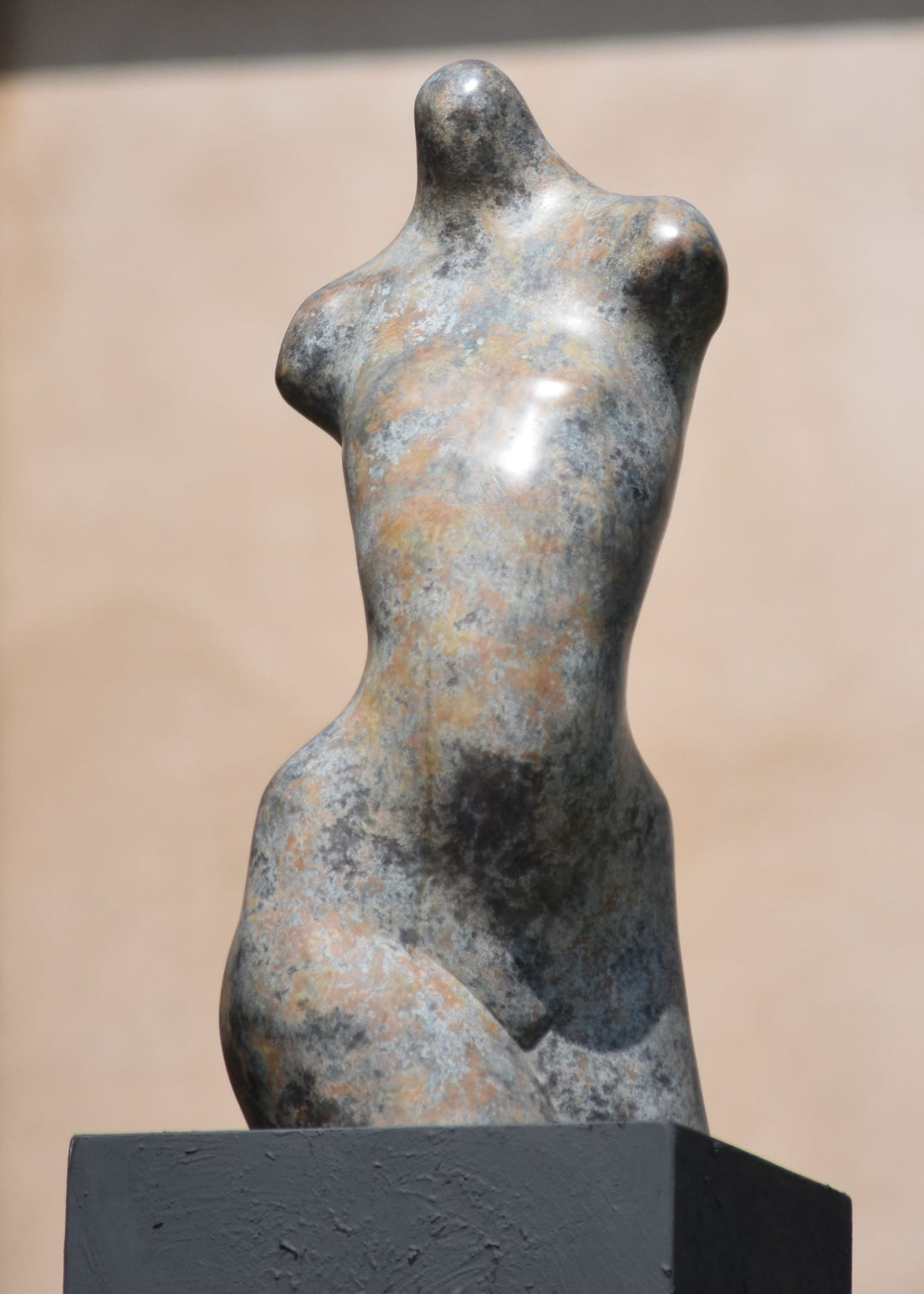 Bronze abstract female torso sculpture by Nicola Godden, with softly curved organic form and smooth hand-finished surface, standing on a plinth outdoors, evoking sensuality, balance and metamorphosis through simplified human anatomy and tactile patination.