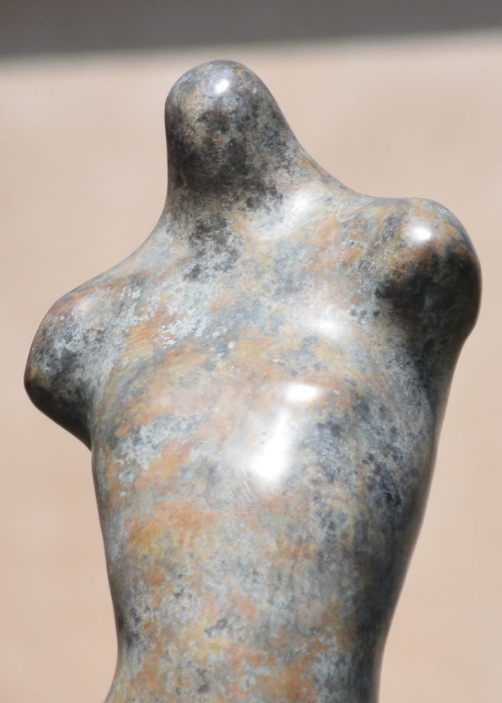 Bronze abstract female torso sculpture by Nicola Godden, with softly curved organic form and smooth hand-finished surface, standing on a plinth outdoors, evoking sensuality, balance and metamorphosis through simplified human anatomy and tactile patination.