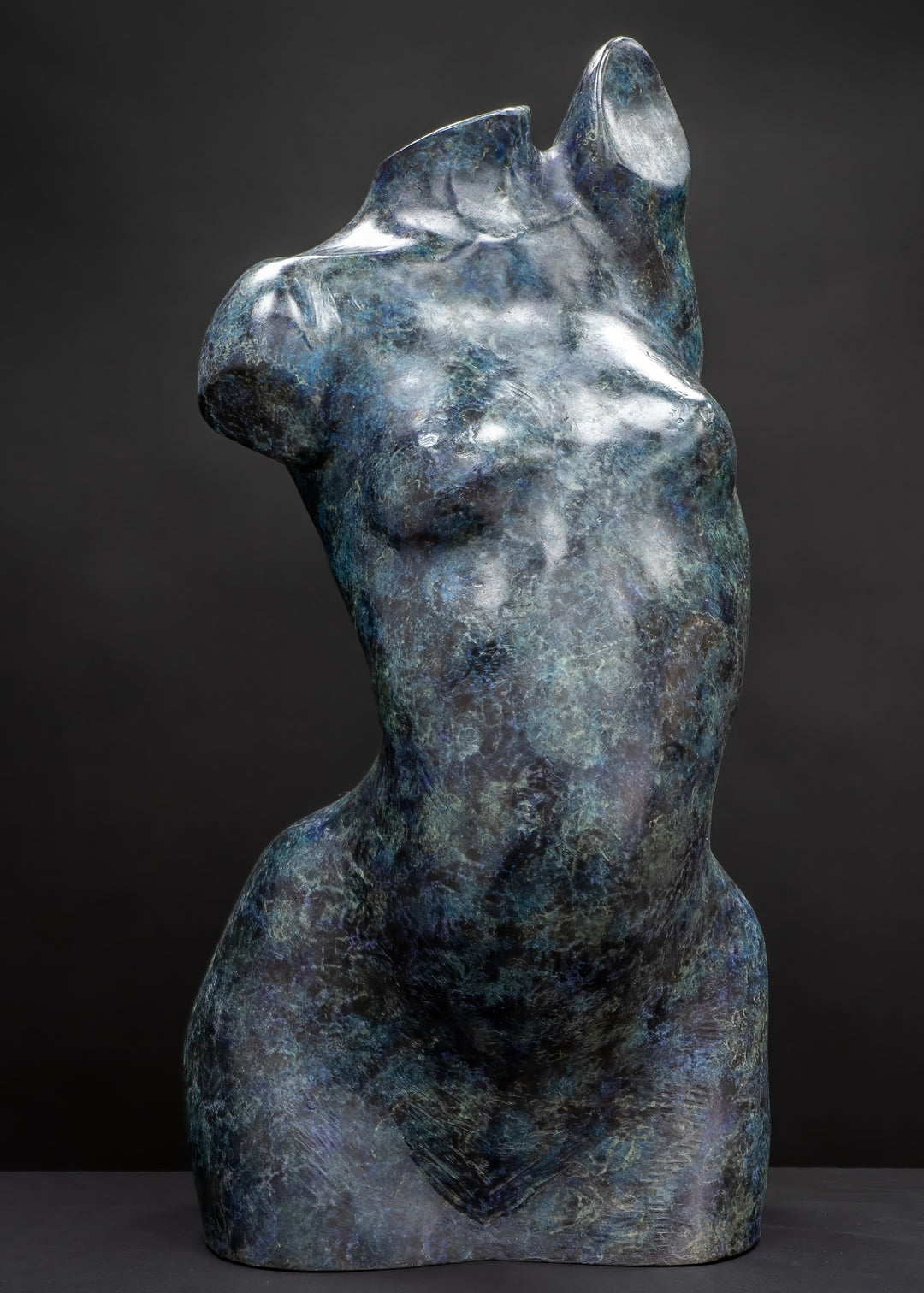 Abstract bronze female torso sculpture by Nicola Godden with flowing organic curves and a polished blue-green patina, standing as a sensual contemporary figurative form designed for garden or exterior display.
