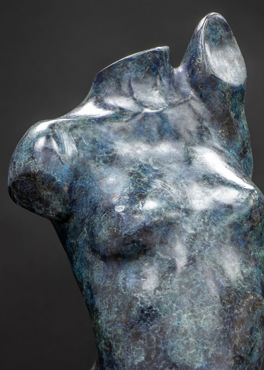 Abstract bronze female torso sculpture by Nicola Godden with flowing organic curves and a polished blue-green patina, standing as a sensual contemporary figurative form designed for garden or exterior display.