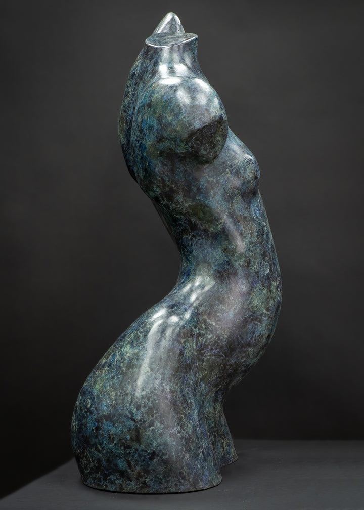 Abstract bronze female torso sculpture by Nicola Godden with flowing organic curves and a polished blue-green patina, standing as a sensual contemporary figurative form designed for garden or exterior display.