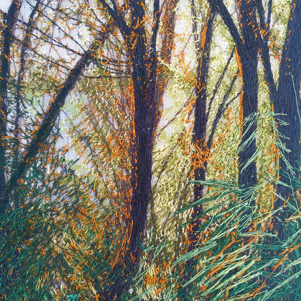 Embroidered woodland with tall trees, golden light filtering through branches, and vivid green and orange grasses in the foreground.