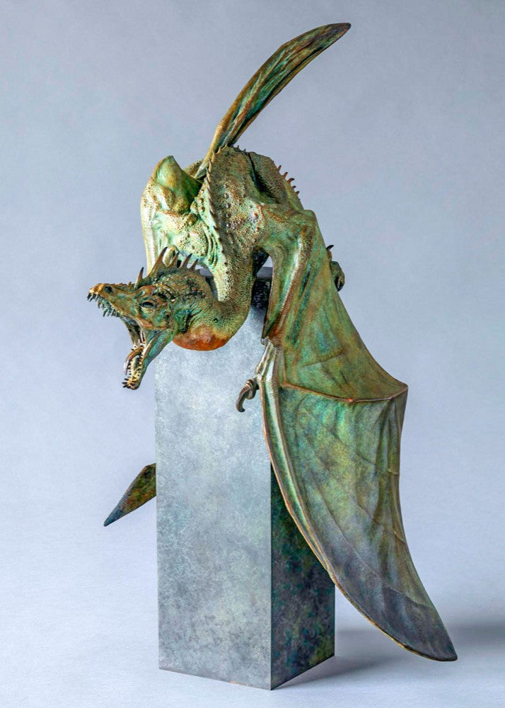 Bronze Firedrake dragon maquette by Nick Bibby, shown mid-leap with outstretched wings, spined tail and verdigris patina, blending anatomical realism with dramatic, creature-like detailing on a tall textured plinth.