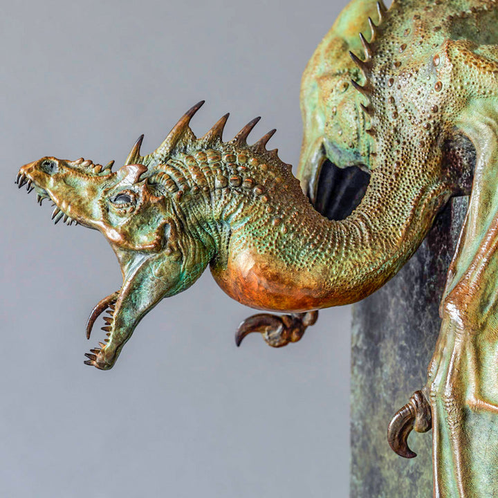 Bronze Firedrake dragon maquette by Nick Bibby, shown mid-leap with outstretched wings, spined tail and verdigris patina, blending anatomical realism with dramatic, creature-like detailing on a tall textured plinth.