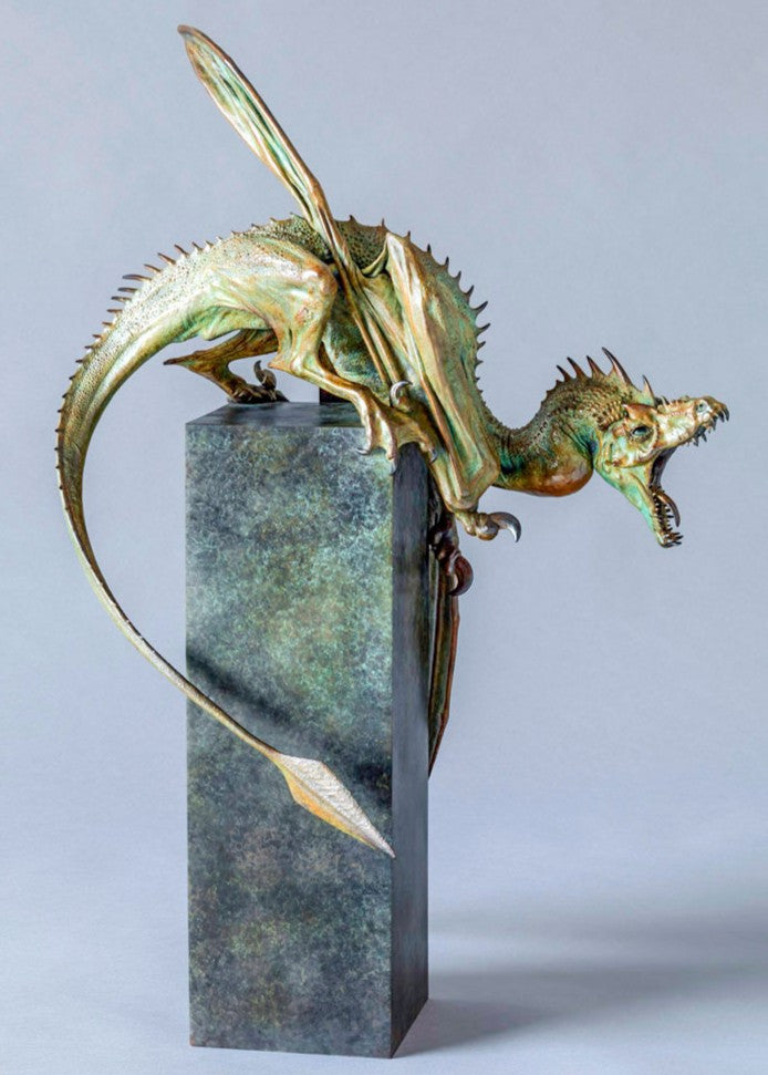 Bronze Firedrake dragon maquette by Nick Bibby, shown mid-leap with outstretched wings, spined tail and verdigris patina, blending anatomical realism with dramatic, creature-like detailing on a tall textured plinth.