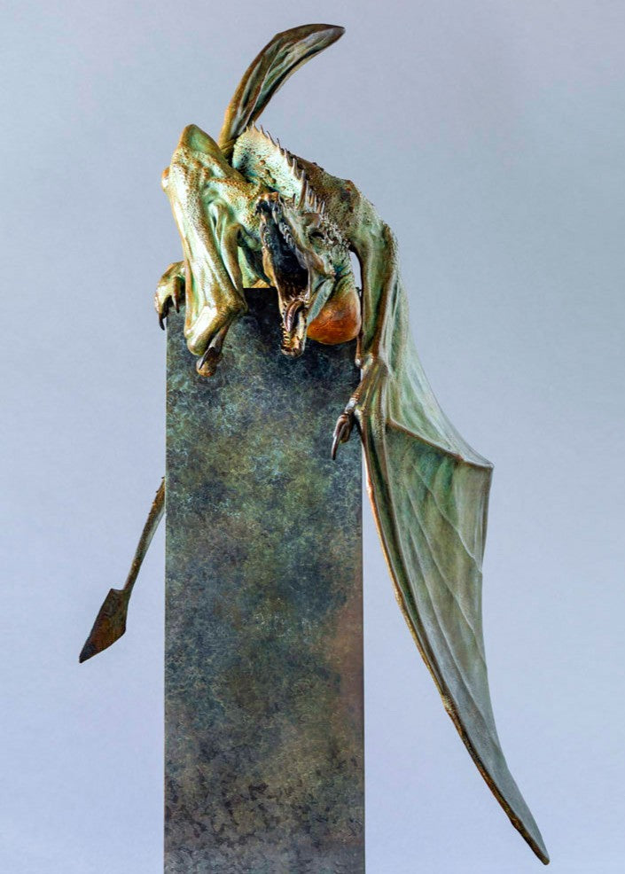 Bronze Firedrake dragon maquette by Nick Bibby, shown mid-leap with outstretched wings, spined tail and verdigris patina, blending anatomical realism with dramatic, creature-like detailing on a tall textured plinth.
