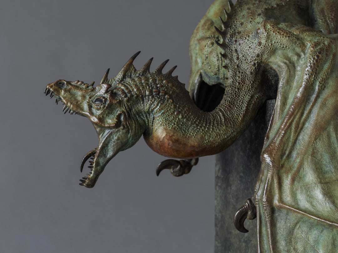 Bronze Firedrake dragon maquette by Nick Bibby, shown mid-leap with outstretched wings, spined tail and verdigris patina, blending anatomical realism with dramatic, creature-like detailing on a tall textured plinth.