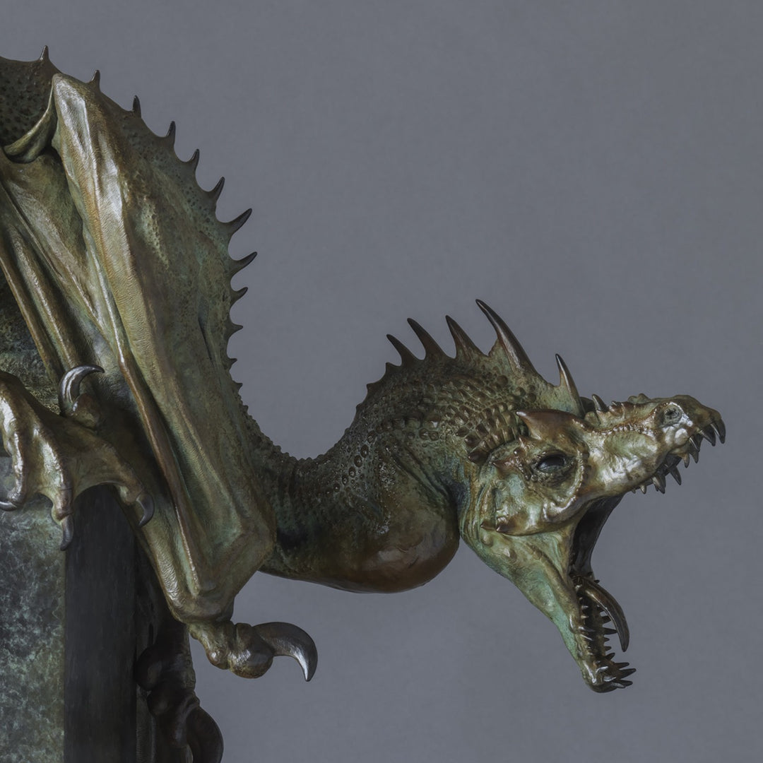 Bronze Firedrake dragon maquette by Nick Bibby, shown mid-leap with outstretched wings, spined tail and verdigris patina, blending anatomical realism with dramatic, creature-like detailing on a tall textured plinth.
