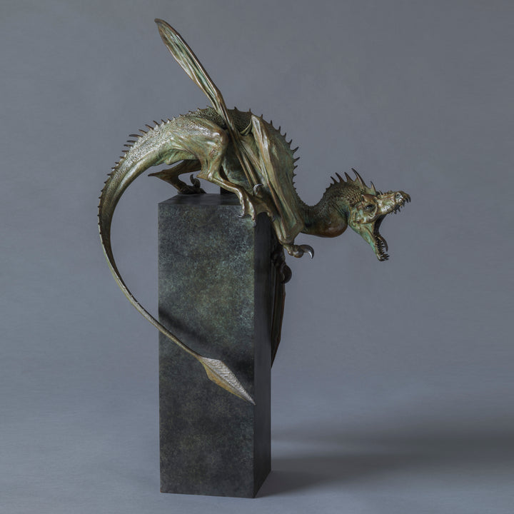 Bronze Firedrake dragon maquette by Nick Bibby, shown mid-leap with outstretched wings, spined tail and verdigris patina, blending anatomical realism with dramatic, creature-like detailing on a tall textured plinth.