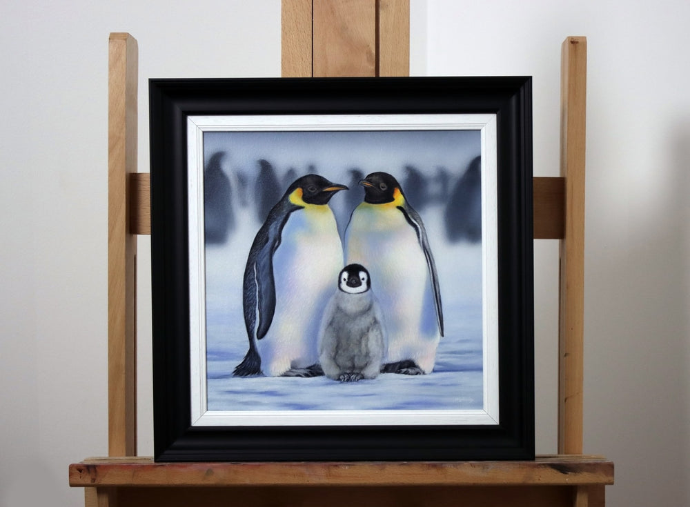 Painting of two adult emperor penguins standing protectively over a fluffy chick in a snowy landscape.