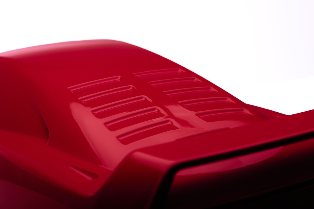 ‘Ferrari F40’ by Srini Gandra, a limited-edition contemporary automotive sculpture from the Forme di Velocità series, inspired by the legendary Ferrari F40, the final Ferrari personally approved by Enzo Ferrari. Presented in a striking high-gloss Rosso Corsa red finish, the sculpture captures the supercar's low wedge-shaped profile, sculpted bonnet, aerodynamic side intakes, distinctive rear engine vents and iconic elevated rear wing. Its smooth, minimalist surfaces celebrate the raw performance, aerodynami