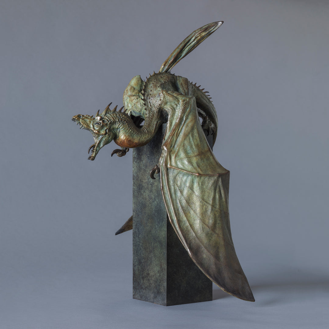 Bronze Firedrake dragon maquette by Nick Bibby, shown mid-leap with outstretched wings, spined tail and verdigris patina, blending anatomical realism with dramatic, creature-like detailing on a tall textured plinth.
