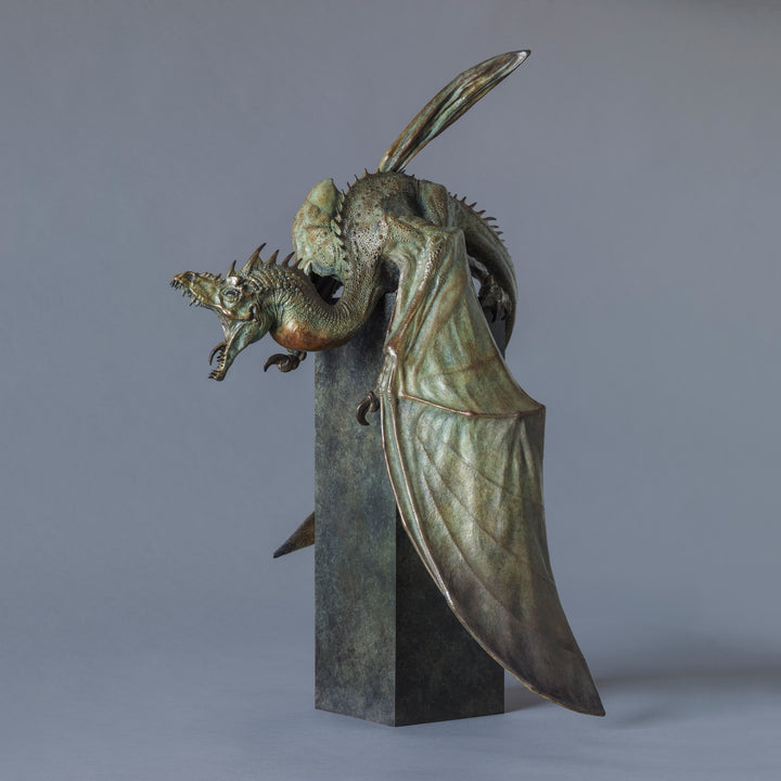 Bronze Firedrake dragon maquette by Nick Bibby, shown mid-leap with outstretched wings, spined tail and verdigris patina, blending anatomical realism with dramatic, creature-like detailing on a tall textured plinth.