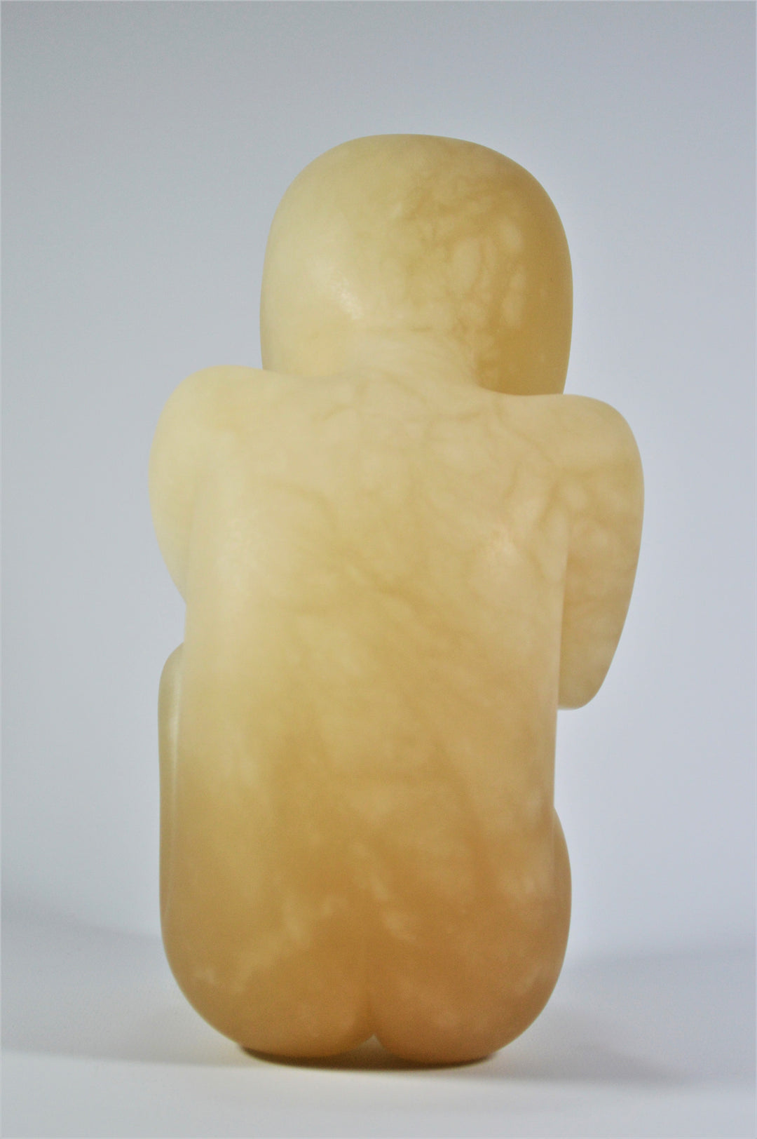 Deborah Harrison alabaster sculpture Foetus, one-off hand-carved work in translucent champagne alabaster, depicting a curled unborn child in the womb-like position, with soft organic form and warm golden glow, symbolising life, vulnerability, and spiritual beginnings.