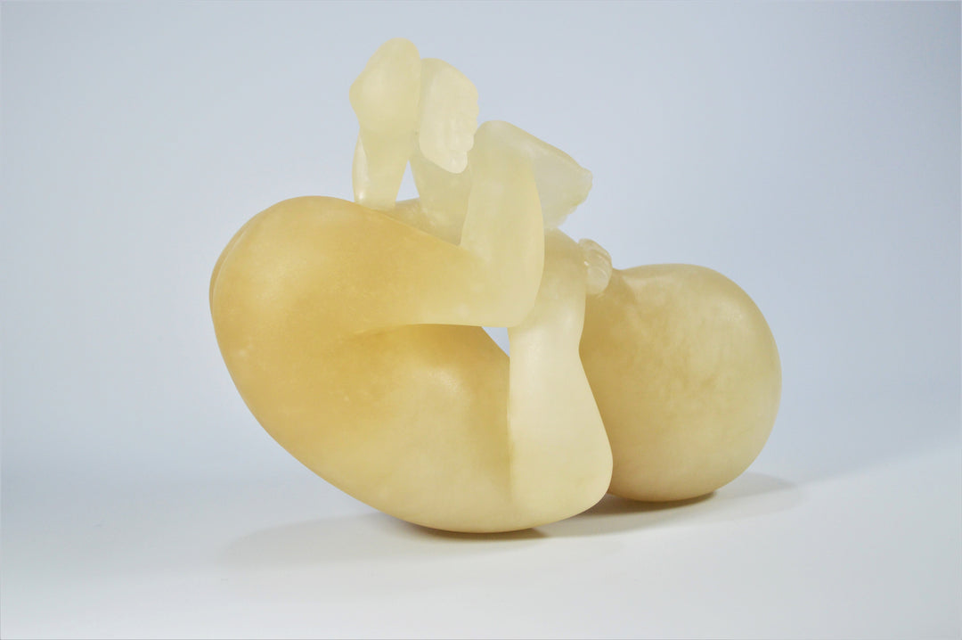 Deborah Harrison alabaster sculpture Foetus, one-off hand-carved work in translucent champagne alabaster, depicting a curled unborn child in the womb-like position, with soft organic form and warm golden glow, symbolising life, vulnerability, and spiritual beginnings.
