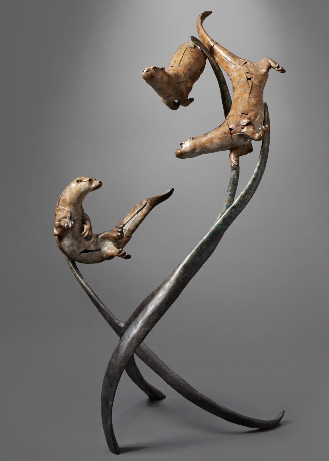 Large bronze wildlife sculpture by Fred Gordon titled Diving Otters. The piece features four otters in dynamic motion, twisting and diving around tall, fluid bronze stems that evoke both water currents and reeds. Each otter is captured mid-leap, with finely observed anatomy and playful expressions, celebrating the agility and character of these aquatic animals. Standing 160cm high, this monumental limited edition sculpture of 9 is signed and numbered, combining realism to create a striking statement piece.