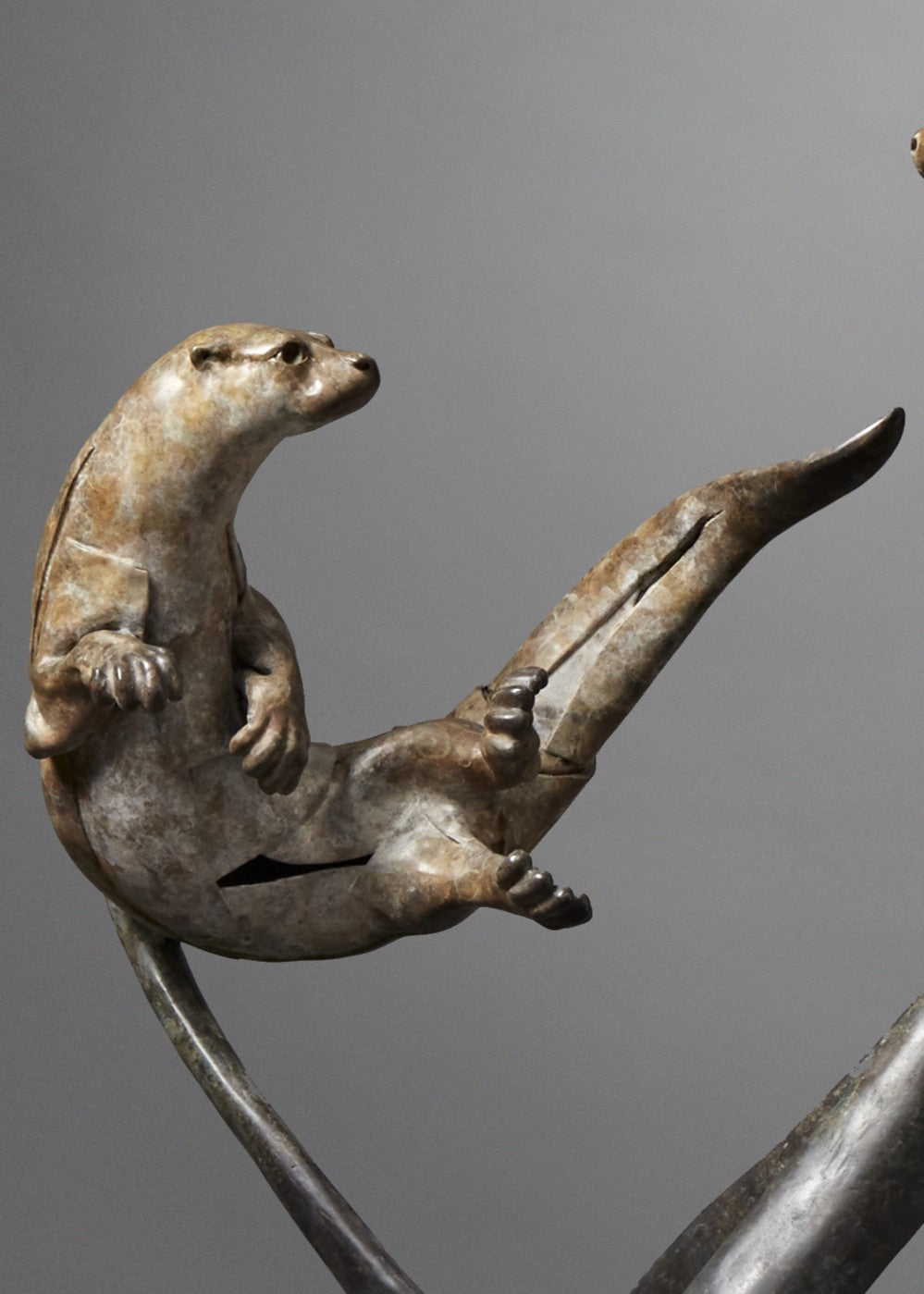 Large bronze wildlife sculpture by Fred Gordon titled Diving Otters. The piece features four otters in dynamic motion, twisting and diving around tall, fluid bronze stems that evoke both water currents and reeds. Each otter is captured mid-leap, with finely observed anatomy and playful expressions, celebrating the agility and character of these aquatic animals. Standing 160cm high, this monumental limited edition sculpture of 9 is signed and numbered, combining realism to create a striking statement piece.