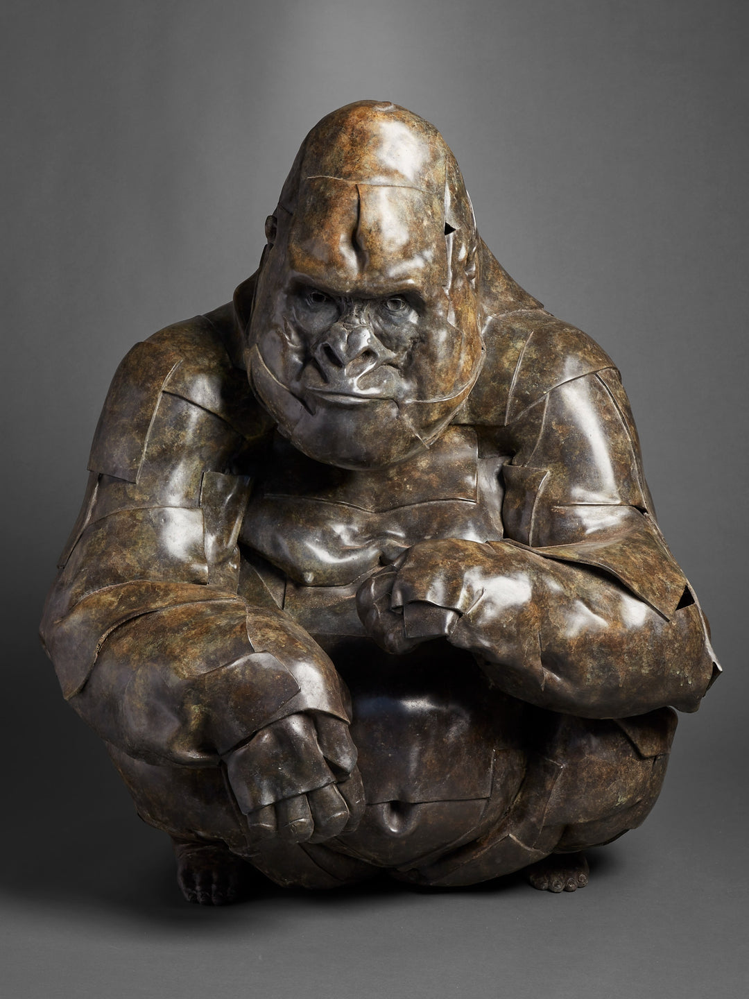Monumental bronze sculpture by Fred Gordon titled Silverback Gorilla. The piece depicts a life-size gorilla in a crouched position, its powerful form captured with layered, faceted bronze planes that emphasise both strength and vulnerability. The textured patina ranges from deep bronze to subtle green undertones, highlighting the gorilla’s muscular presence and expressive face. At 110cm tall, this signed and numbered limited edition of 9 embodies Gordon’s mastery in wildlife sculpture.
