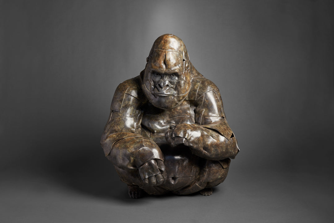 Monumental bronze sculpture by Fred Gordon titled Silverback Gorilla. The piece depicts a life-size gorilla in a crouched position, its powerful form captured with layered, faceted bronze planes that emphasise both strength and vulnerability. The textured patina ranges from deep bronze to subtle green undertones, highlighting the gorilla’s muscular presence and expressive face. At 110cm tall, this signed and numbered limited edition of 9 embodies Gordon’s mastery in wildlife sculpture.