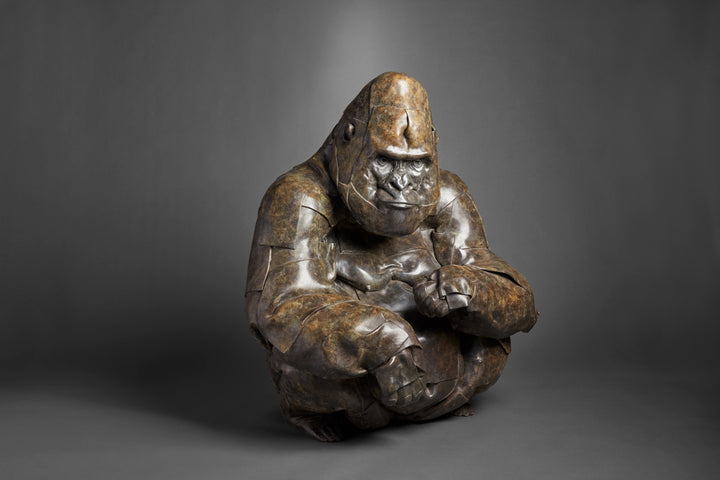 Monumental bronze sculpture by Fred Gordon titled Silverback Gorilla. The piece depicts a life-size gorilla in a crouched position, its powerful form captured with layered, faceted bronze planes that emphasise both strength and vulnerability. The textured patina ranges from deep bronze to subtle green undertones, highlighting the gorilla’s muscular presence and expressive face. At 110cm tall, this signed and numbered limited edition of 9 embodies Gordon’s mastery in wildlife sculpture.