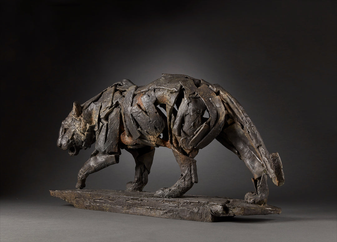 Limited edition bronze sculpture of a walking tiger by Fred Gordon. The piece shows the tiger mid-stride, muscles and movement captured through layered bronze planes that give a sense of both strength and fluidity. Rich dark patinas with earthy highlights emphasise the texture of the bronze, evoking the raw power and grace of this endangered predator. Signed and numbered in an edition of 12, the sculpture blends realism with abstraction, making it a striking wildlife artwork.