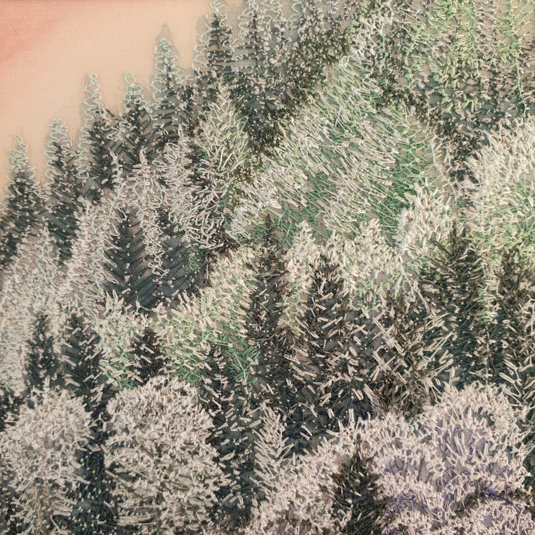 Layered embroidered forest scene with dense pine trees in muted shades of lavender, green, and deep navy thread.
