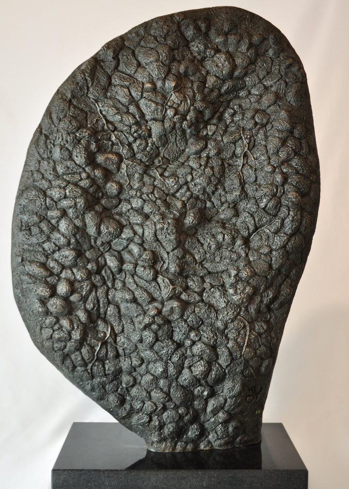 A hand-painted bronze bas-relief sculpture depicting a reclining female form emerging from dense spring foliage, with leaves, ferns and flowers flowing across her body, blending seamlessly into textured earth around the edge.