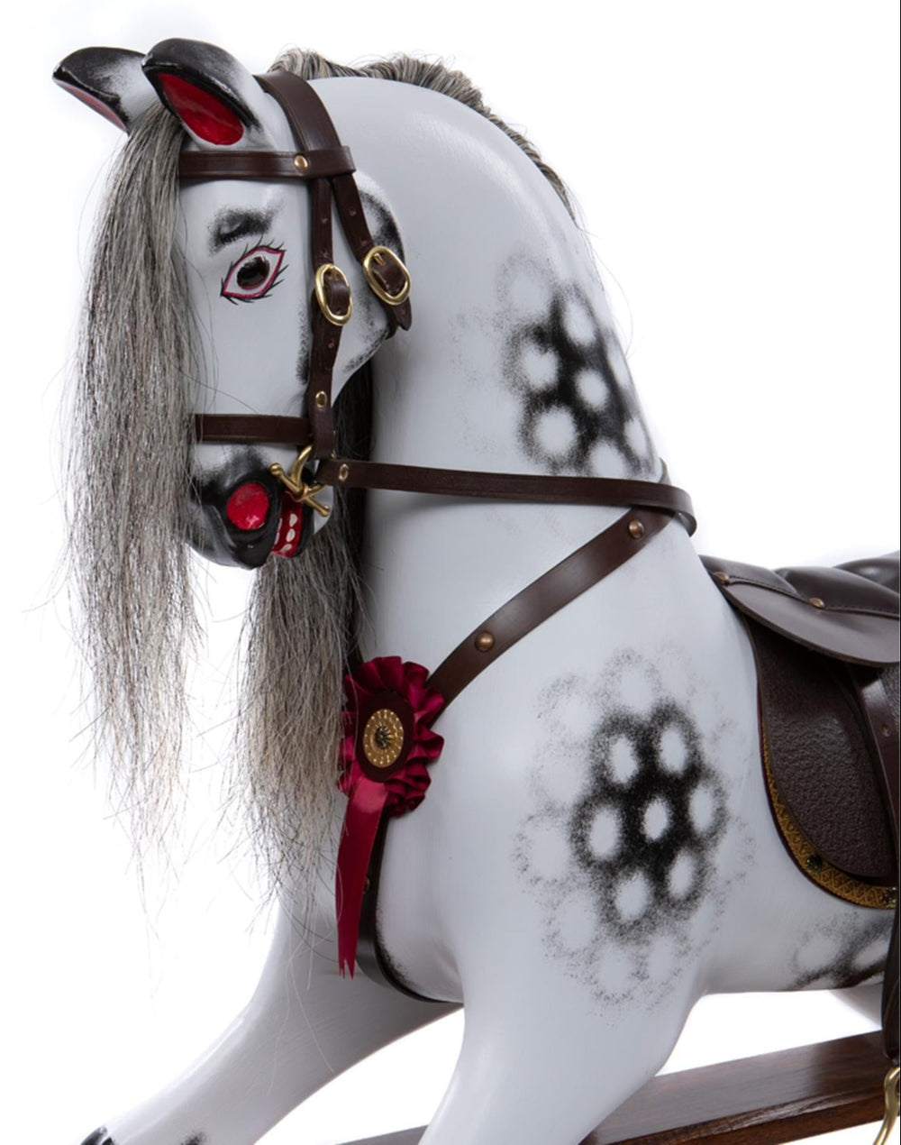 White rocking horse with stylised black dapples, grey mane, and rich burgundy leather tack on a polished oak safety stand.

