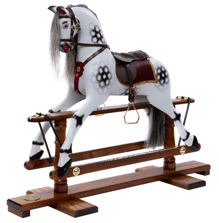 White rocking horse with stylised black dapples, grey mane, and rich burgundy leather tack on a polished oak safety stand.

