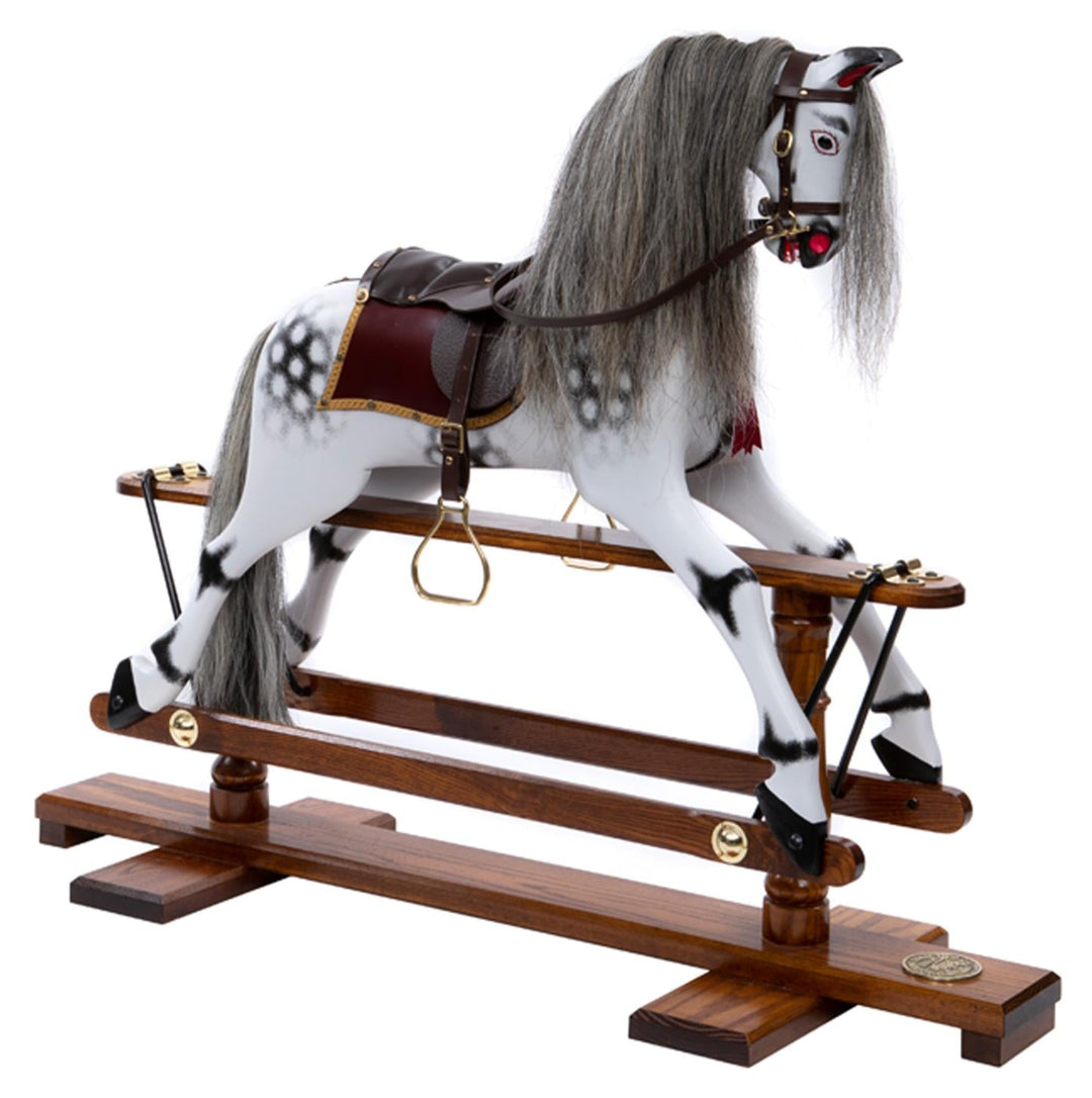 White rocking horse with stylised black dapples, grey mane, and rich burgundy leather tack on a polished oak safety stand.

